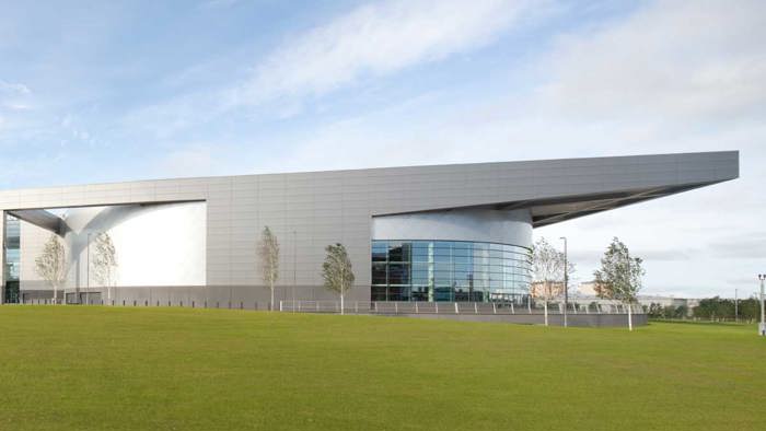Exterior shot of Glasgow Club Emirates Arena with green grass in foreground and blue sky in background 