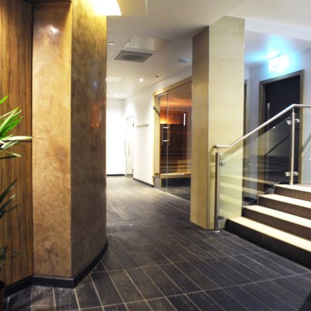 The interior of a spa with tiles, glass, plants and warm coloured lighting