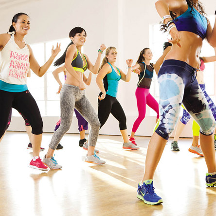Group class in colourful gym wear dancing and smiling
