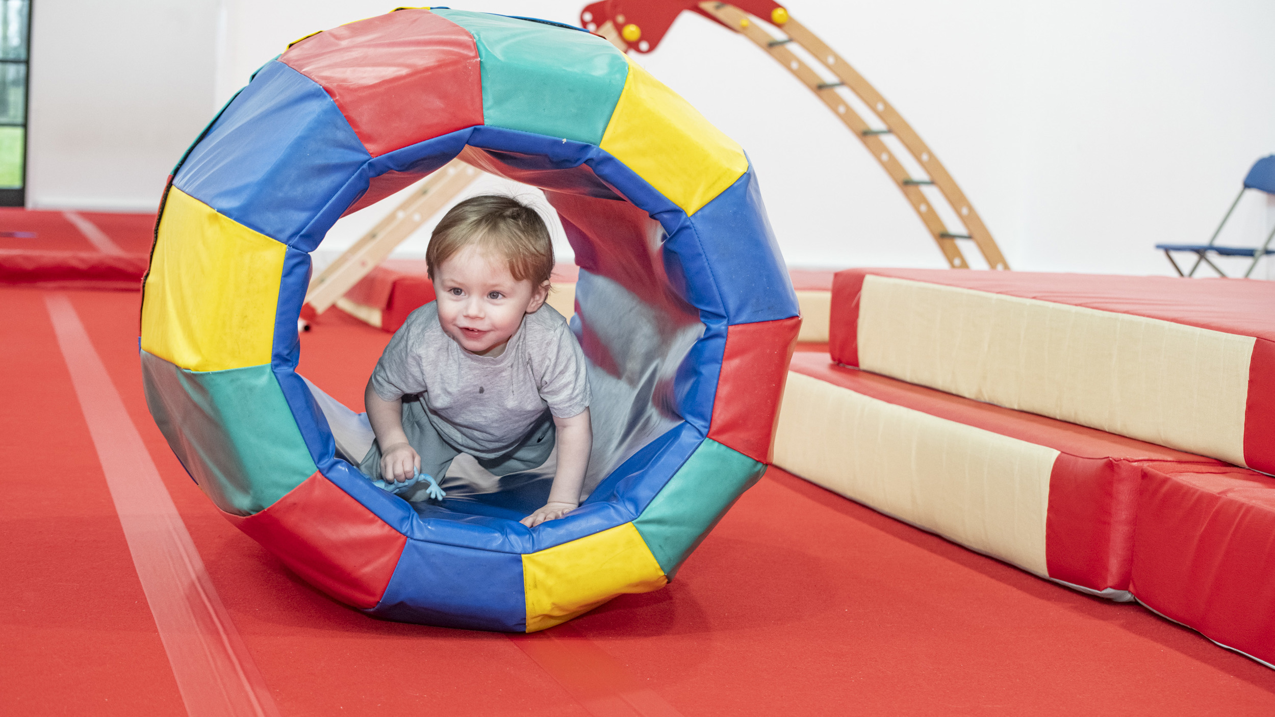 Small child climbing through colourful tunnel 