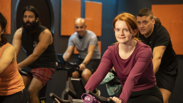 A group of people on spin bikes in lit spin studio 