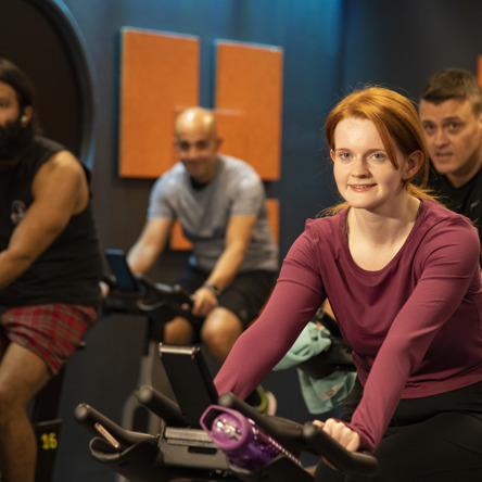 A group of people on spin bikes in lit spin studio 