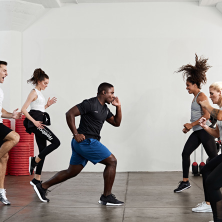 A group of people in a fitness studio lunging in body attack class