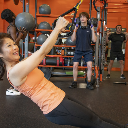 Group strength training, person if foreground doing pull ups 