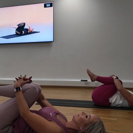 A group of people in a fitness studio following an on-screen virtual class