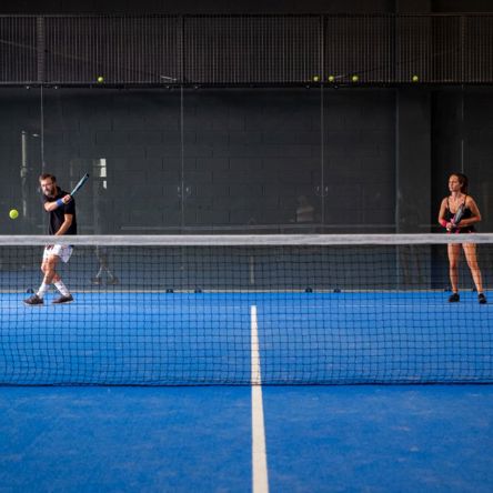 Two padel tennis players on a blue padel court