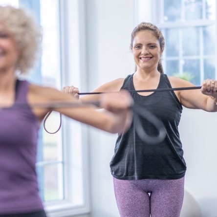 Two people holding resistance bands and smiling 