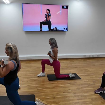 A group of people in a fitness studio following an on-screen virtual class