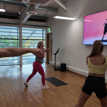 A group of people in a fitness studio following an on-screen virtual class