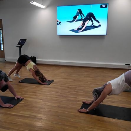 A group of people in a fitness studio following an on-screen virtual class