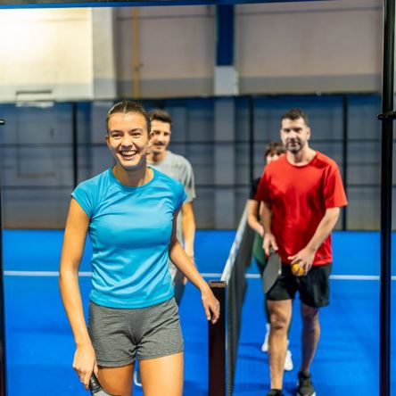 A group of padel tennis players smiling as they leave the court