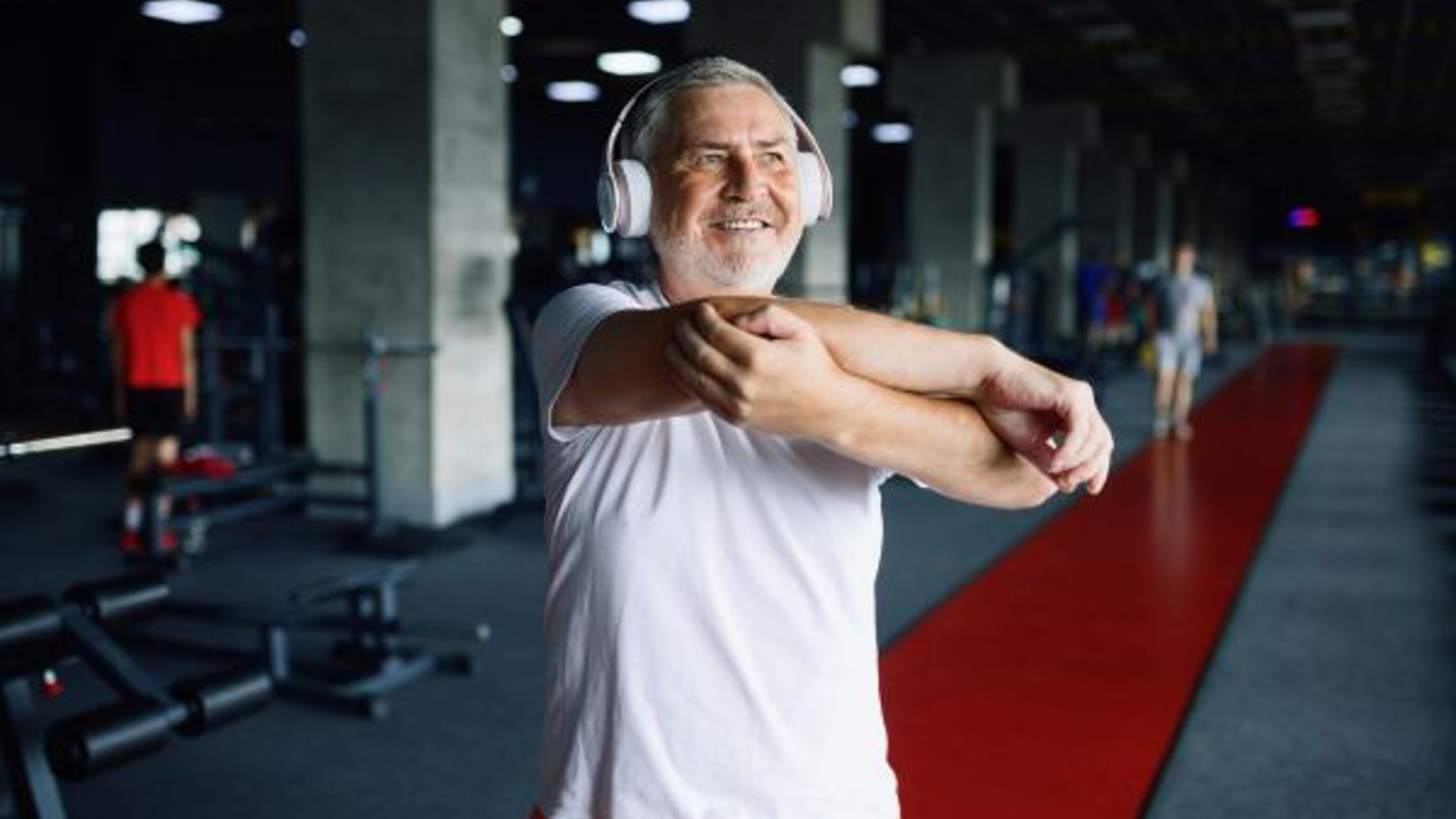 Someone wearing headphones while stretching in a gym