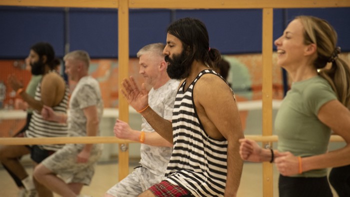 A group of participants in a fitness studio taking part in a Circuit class. They're  running on the spot and lifting their knees high 