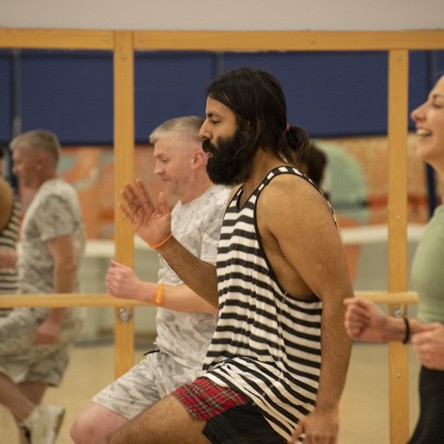 A group of participants in a fitness studio taking part in a Circuit class. They're  running on the spot and lifting their knees high 