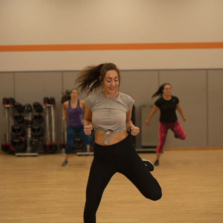 Person centre in group fitness class lifting leg in motion