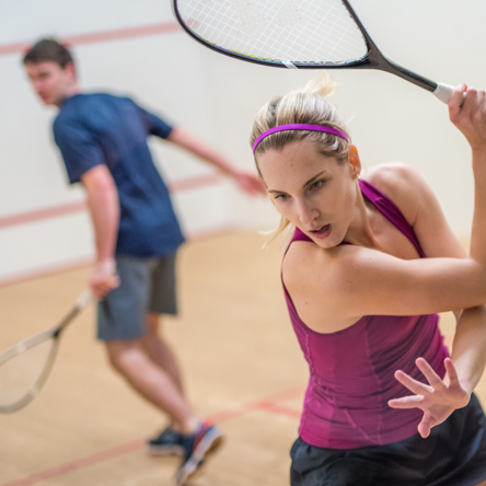 Two people on Squash court holding racket in motion