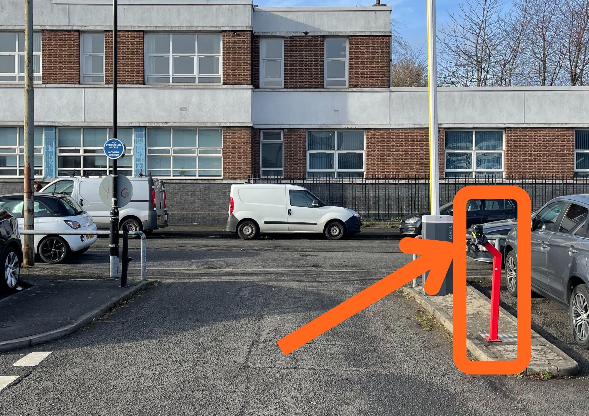 the exit to a car park with a barrier and, circled in orange, a keypad to enter a code to open it