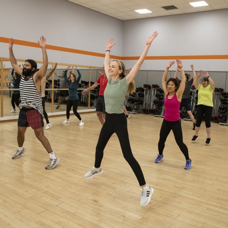 Group of people in fitness class doing star jumps 