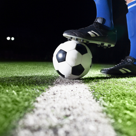 Foot on top of football on pitch line 