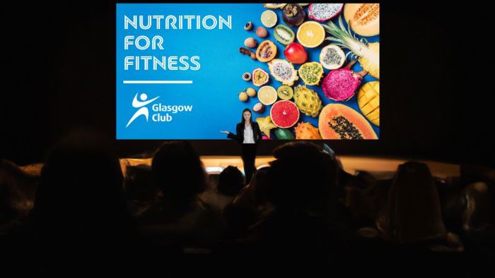 A presenter on stage delivering a talk about nutrition for fitness