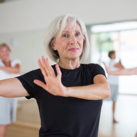 Person in foreground of dance class swinging arms to the side 