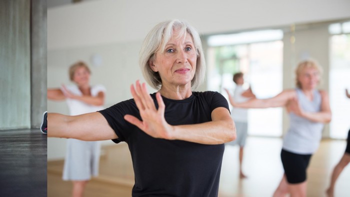 Person in foreground of dance class swinging arms to the side 