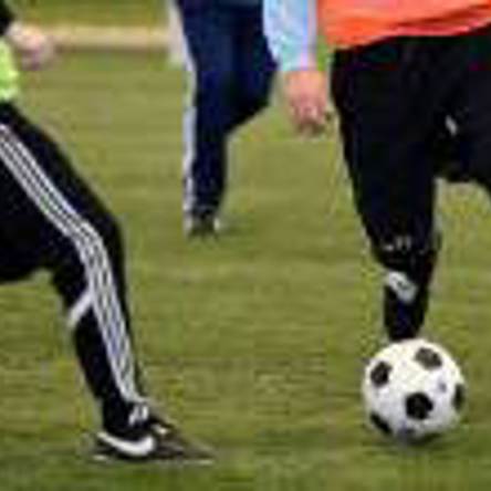 Two people's lower body/legs tackling football