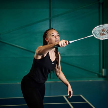 A young person hitting a shuttlecock with a badminton racquet